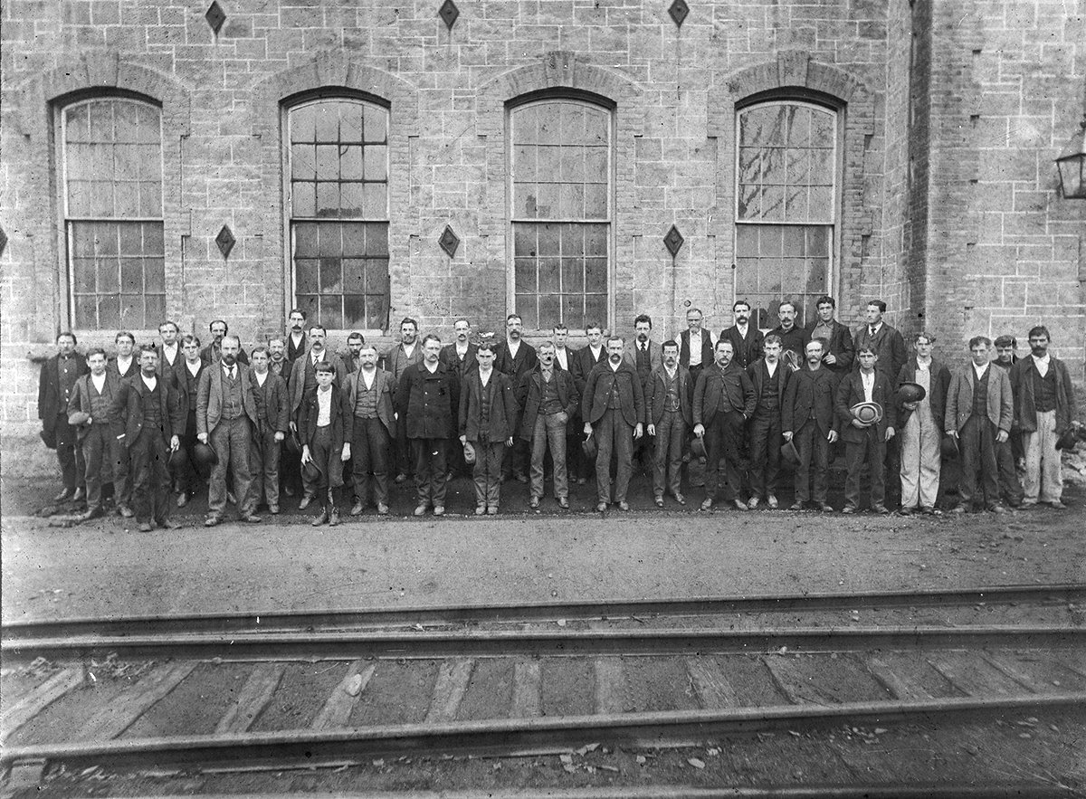 Workers pose in front of the new train tracks in front of Building 3 circa 1900
